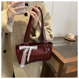 Détail du sac Boston en cuir verni bordeaux avec nœud en dentelle blanche et rivets argentés