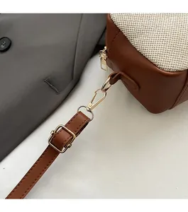 Detail of golden metal hardware buckle and adjustable brown leather shoulder strap on bag