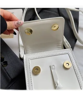 Detail view of white PU leather mini bag showing secure gold magnetic snap closure