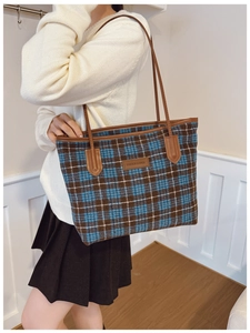Detail of blue and brown tweed tote bag showing woven texture and leather strap