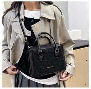 Detail of a vintage black textured crossbody bag with gold Fashion Bags text and handles