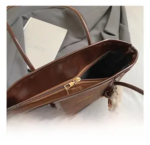 Vista dettagliata della borsa tote in pelle marrone scuro con cerniera dorata e finiture