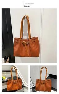 Detail view of brown tote bag with V-shaped weave pattern and leather strap buckles