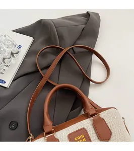 Detail of canvas bowling bag with brown leather handles and logo on grey suit