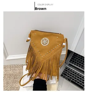 Close-up of brown suede saddle bag with rhinestone flower, gold rivets and long fringe tassels