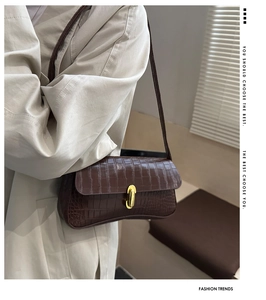 Close-up of deep brown crocodile pattern handbag with golden buckle and sleek leather texture