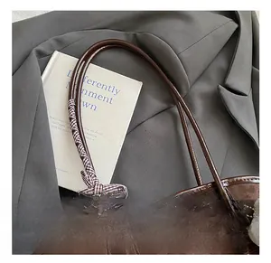 Dettaglio borsa tote marrone caffè con fiocco a scacchi e logo dorato alla moda