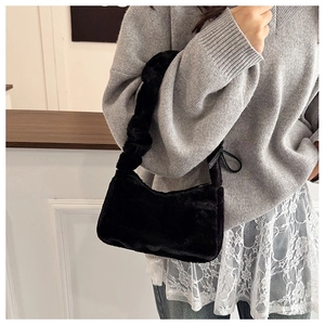 Detail of black faux fur underarm bag with a decorative ribbon bow and ruffled strap