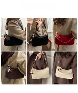 Detail view of stylish leather underarm bags in four colors with cherry charm and gold chain