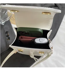 Interior view of white crossbody bag showing storage for phone, wallet and lipstick