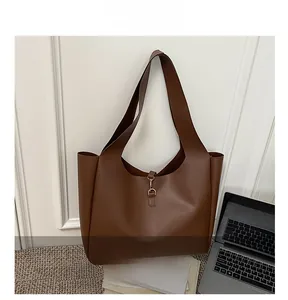 Detail of dark brown tote bag showing smooth matte leather and elegant metal hook closure