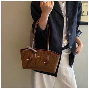 Borsa tote leopardata marrone con scritte dorate e nastro portata da una modella