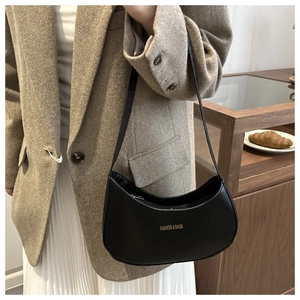 Close-up of minimalist black leather crescent bag with gold lettering on a model
