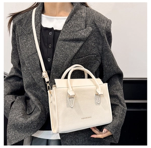 Detail of minimalist cream shoulder bag featuring adjustable strap and leather texture