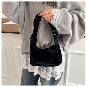 Detail of black plush underarm bag with decorative bow and soft faux fur texture