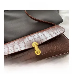 Close-up of vintage brown crocodile texture and gold U-shaped metal buckle on shoulder bag