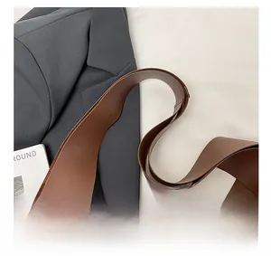 Close-up of the wide shoulder strap and soft brown leather texture on a tote bag