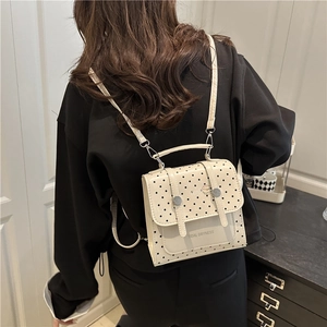 Polka dot mini backpack in cream with adjustable straps shown on model from back view
