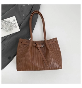Close-up of brown tote bag with herringbone texture and silver buckle strap detail