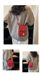 Detail of red leather phone bag with golden Fashion text and metal pendant charm