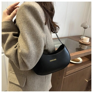 Fashionable black PU leather dumpling bag shown in a lifestyle indoor setting