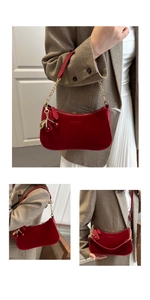 Detail of red suede underarm bag with gold chain strap and decorative cherry charm