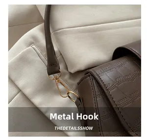 Detailed macro view of the premium golden hardware hook on the brown crocodile pattern bag