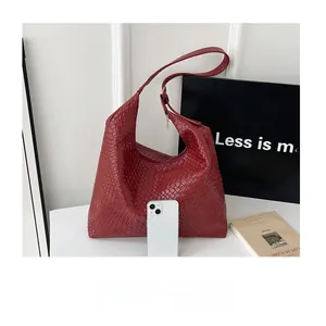 Detail of red woven leather tote bag with white smartphone for size comparison