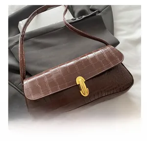 Detail of dark brown crocodile embossed shoulder bag with gold metal buckle closure