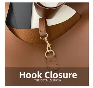 Macro shot of gold metal hook closure and textured brown leather on a tote bag
