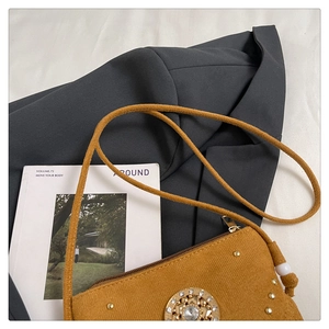 Détail du sac besace ocre avec ornement en strass doré et des rivets métalliques