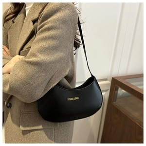 Close-up of a black crescent shoulder bag featuring a minimalist golden logo print