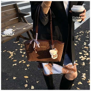 Dettaglio di una borsa tote marrone maculata con ciondolo di peluche e stile autunnale