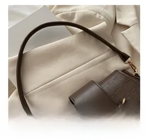 Detail shot of brown crocodile pattern leather handbag with elegant gold metal buckle closure