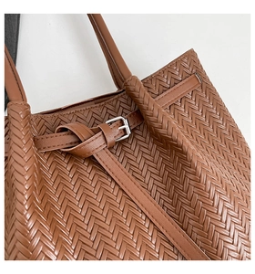 Close-up of caramel brown woven tote bag showing premium texture and buckle detail