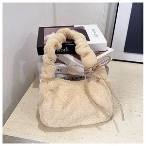 Detail of plush cream shoulder bag featuring faux fur texture and side bow accent