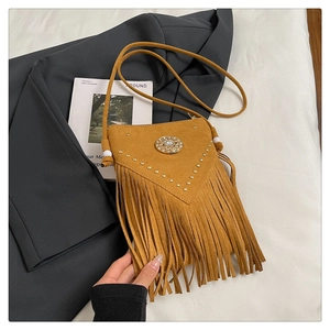 Détail de sac besace en daim marron avec clous, franges bohèmes et boucle ornée de pierre