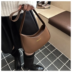 Detail of brown crescent hobo bag featuring golden letter print and smooth texture
