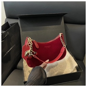 Detail of red velvet hobo bag with gold chain strap and cherry charm in gift box