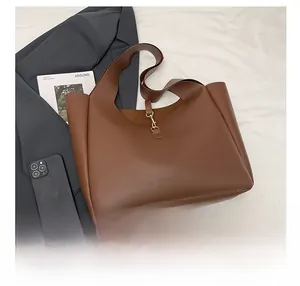 Detailed view of brown leather tote bag with metal hook closure for office commute
