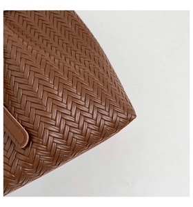 Close-up of caramel brown woven leather texture with precise stitching on tote bag