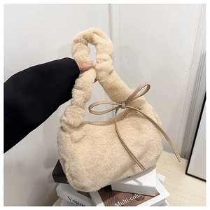 Detailed macro view of beige plush fur handbag featuring a decorative bow and knotted handle