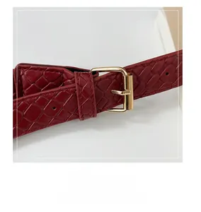 Close-up of a woven dark red leather strap with a polished gold adjustable buckle