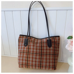 Détail d'un grand sac cabas à carreaux classique avec des bretelles marron robustes