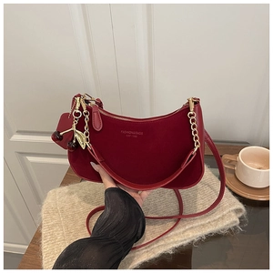 Detail of hobo shoulder bag with leather strap, gold chain, and cherry charm accessory