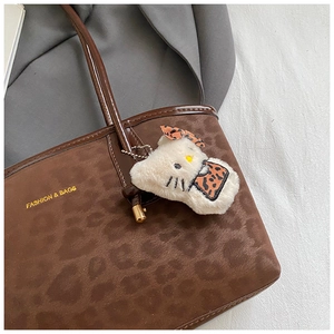 Dettaglio della borsa tote leopardata con ciondolo a forma di gatto e finiture dorate