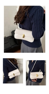 Detail of white crocodile texture underarm bag with gold metal buckle and sleek strap