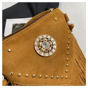 Détail du sac besace bohème avec franges en daim et emblème coeur gravé doré