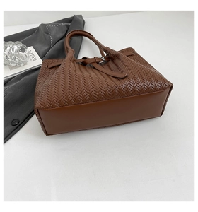 Detail of premium brown woven texture tote bag with metallic buckle and leather handle