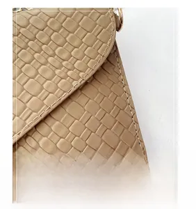 Detail of beige faux leather handbag featuring checkered embossed texture and stitching